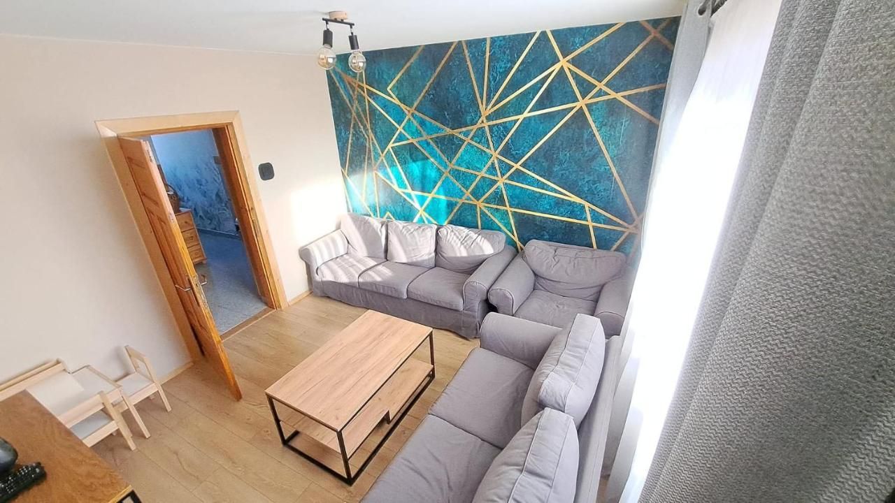 Wspólny salon z szarymi sofami i turkusową ścianą